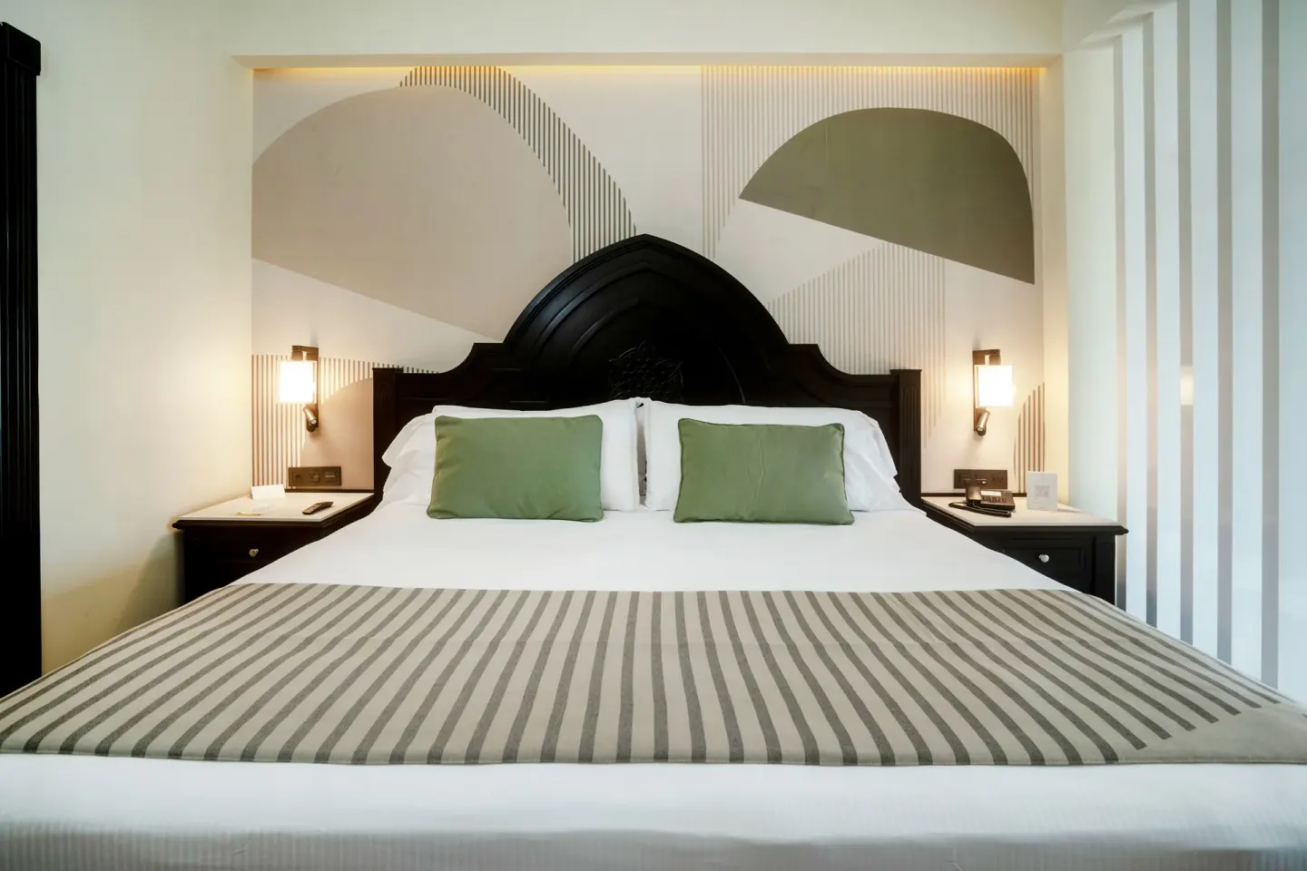 King bed with carved dark headboard and geometric wall panels at Hotel Riu Palace Pacifico.