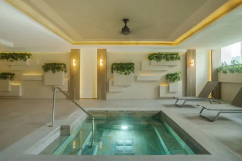 Indoor spa pool with steps, plants, and loungers at Hotel Riu Palace Pacifico.