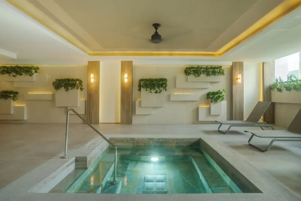 Indoor spa pool with steps, plants, and loungers at Hotel Riu Palace Pacifico.
