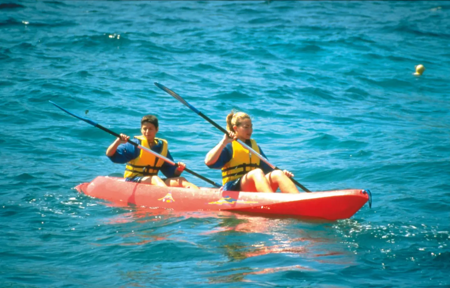 Two guests kayaking on blue ocean water at Hotel Riu Palace Pacifico.