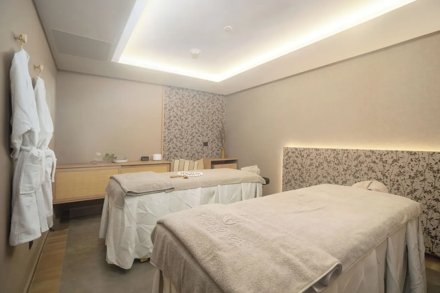 Spa treatment room with two massage tables and robes at Hotel Riu Palace Pacifico.
