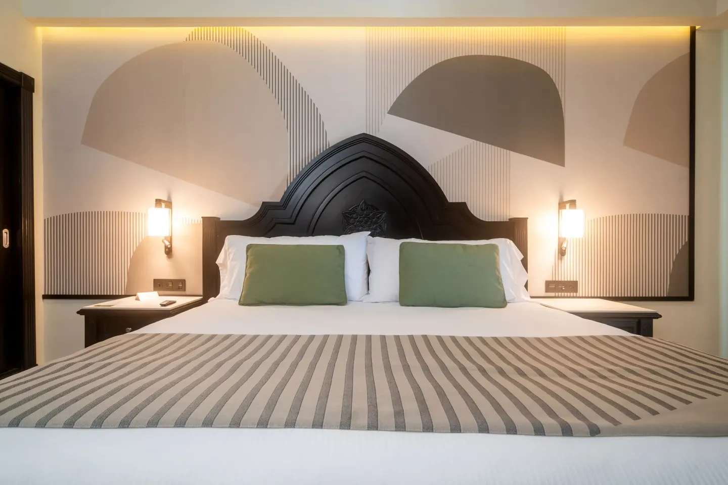 A made bed with green pillows in a bedroom of the Junior Suite 2 Bedrooms at Hotel Riu Palace Pacifico.