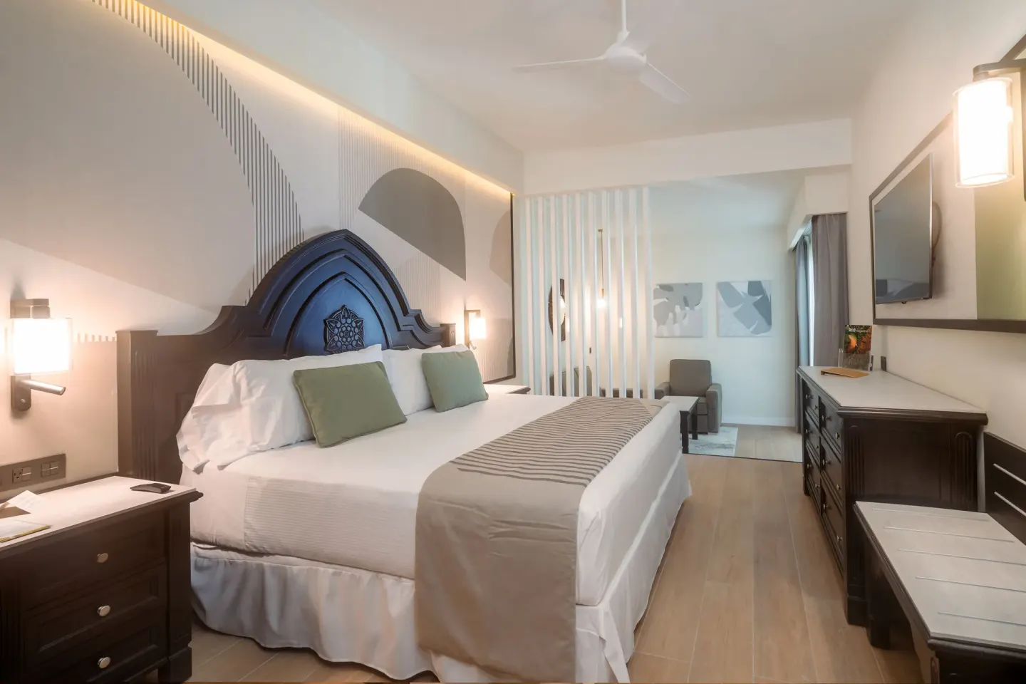 Bedroom of the Junior Suite 2 Bedrooms with bed, dresser, TV, and sitting area at Hotel Riu Palace Pacifico.