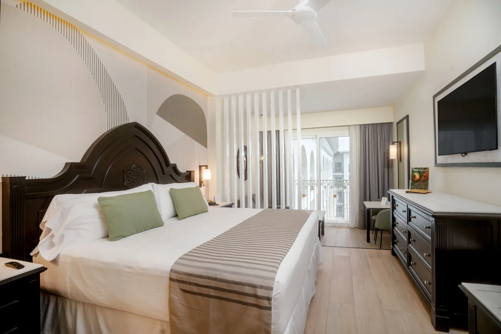 Junior Suite with king bed, balcony doors, dresser and TV at Hotel Riu Palace Pacifico.