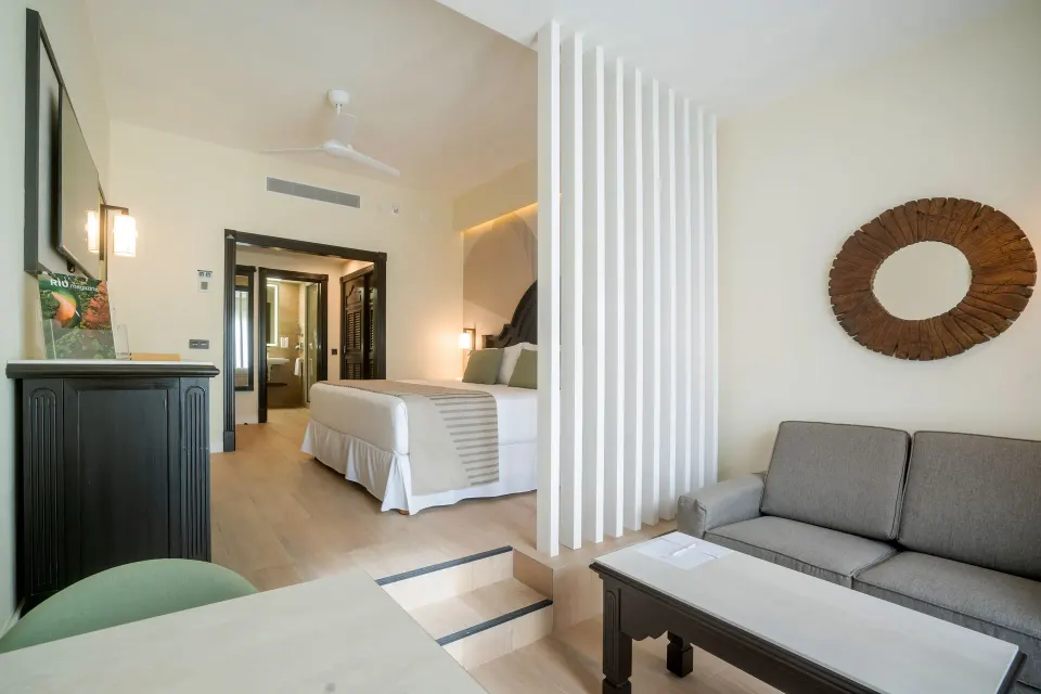 Junior Suite seating area with sofa, coffee table and bed beyond at Hotel Riu Palace Pacifico.