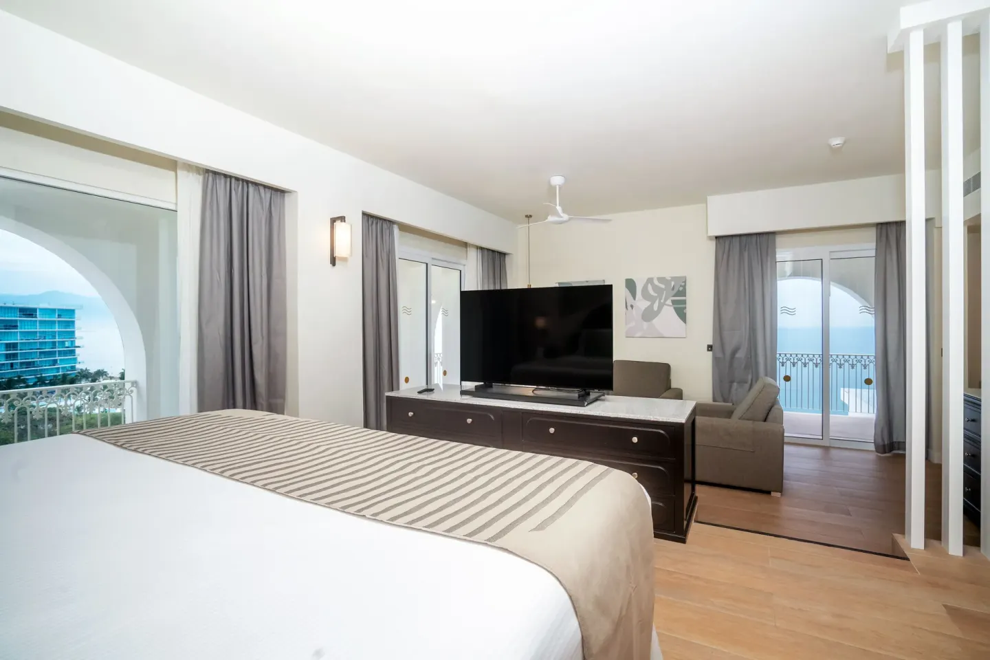 Oceanfront suite bedroom with king bed, TV, sofa, and balcony at Hotel Riu Palace Pacifico.