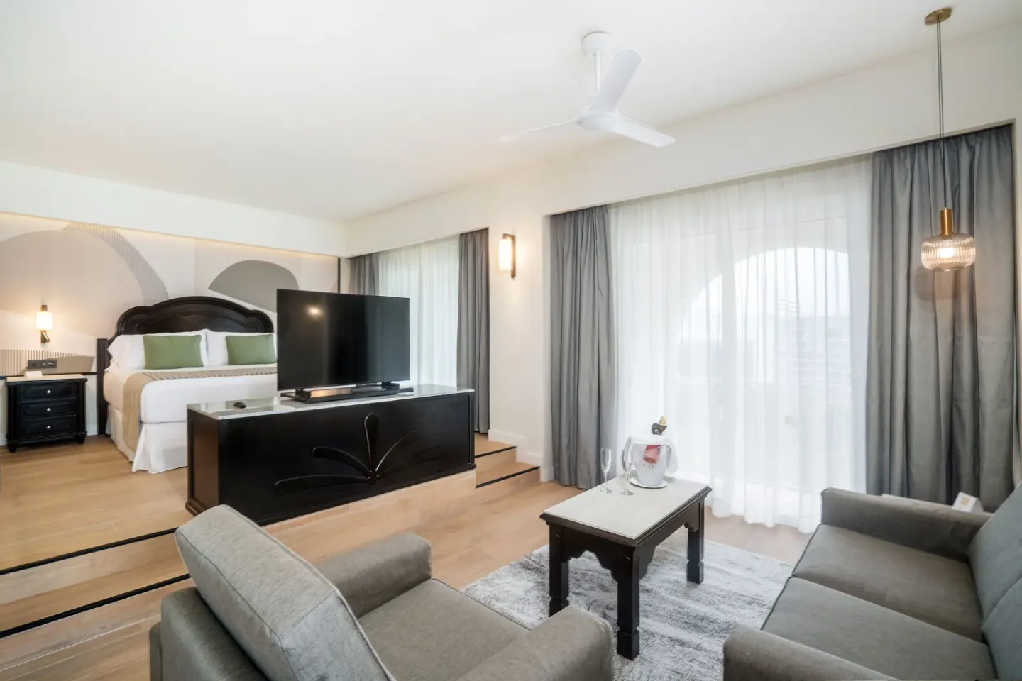 Oceanfront suite living area with king bed, sofa, TV, and balcony at Hotel Riu Palace Pacifico.