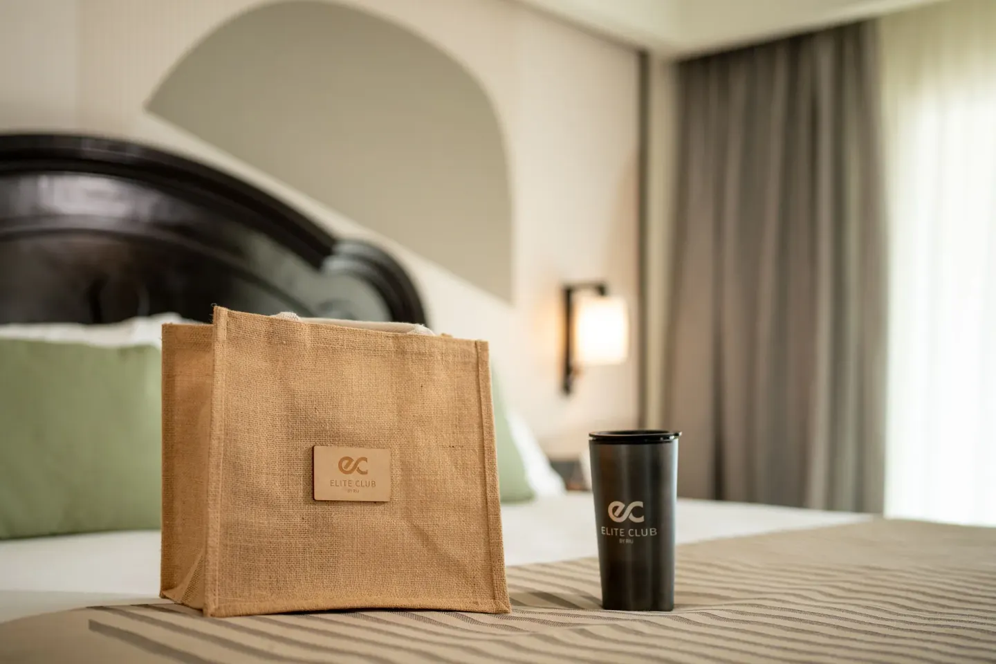Elite Club tote and tumbler displayed on a suite bed at Hotel Riu Palace Pacifico.