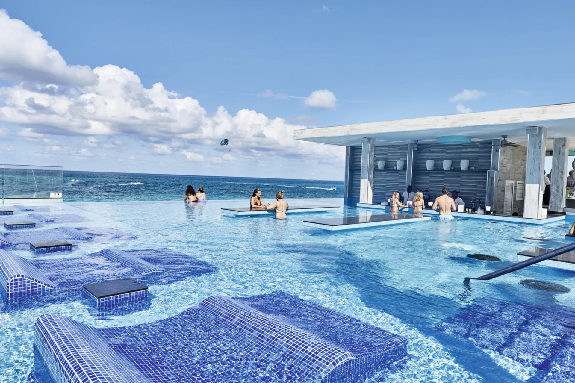 Infinity pool with swim-up bar and ocean backdrop at Hotel Riu Palace Paradise Island.