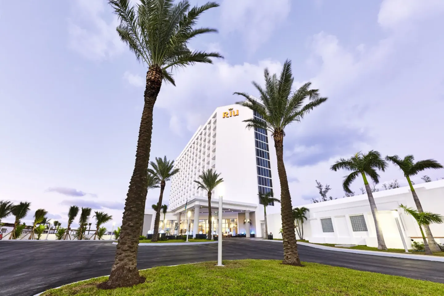 Palm-lined exterior driveway and tower at Hotel Riu Palace Paradise Island.