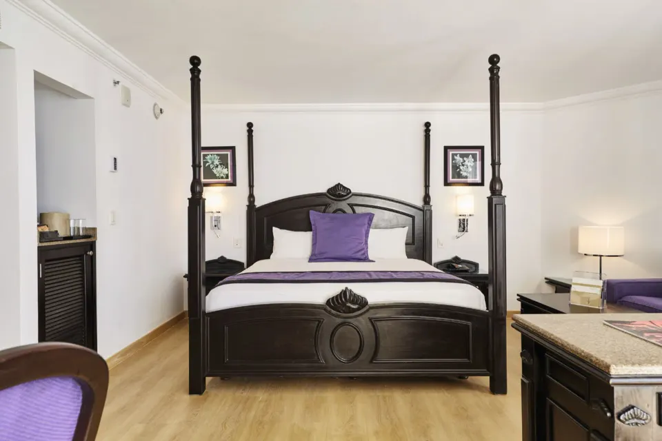 Junior Suite Oceanfront four-poster bed with bedside tables at Hotel Riu Palace Paradise Island.
