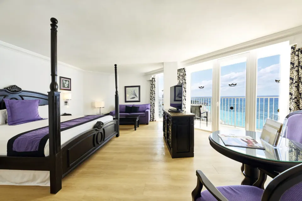 Junior Suite Oceanfront with four-poster bed, seating, balcony, and ocean view at Hotel Riu Palace Paradise Island.