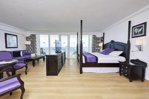 Oceanfront Suite with four-poster king bed and balcony at Hotel Riu Palace Paradise Island.