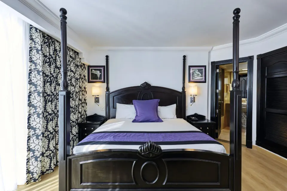 Standard Suite king bed with dark wood posts at Hotel Riu Palace Paradise Island.