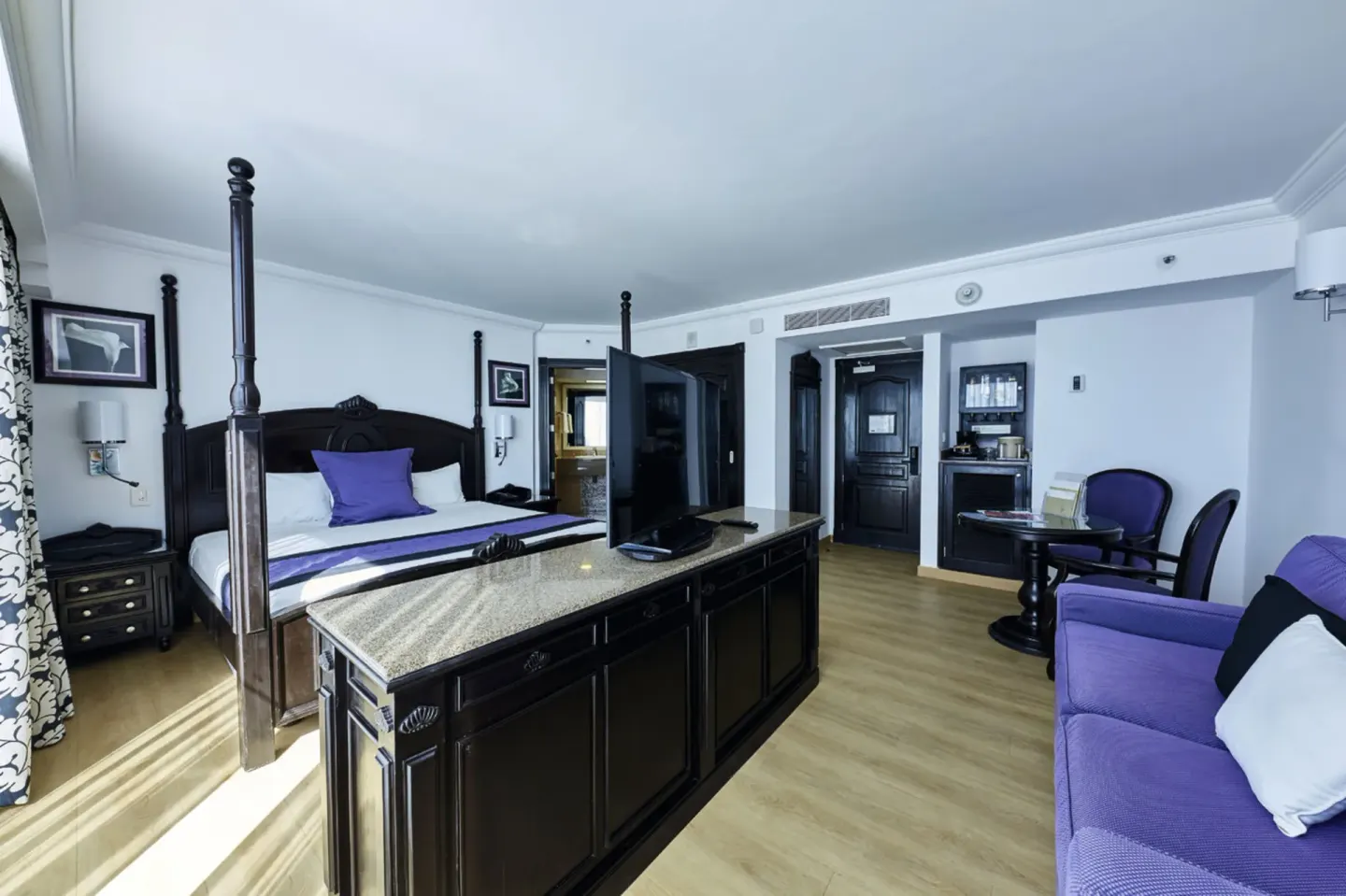 Standard Suite with king bed and purple sofa at Hotel Riu Palace Paradise Island.