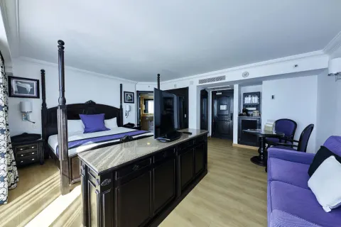 Standard Suite with king bed and purple sofa at Hotel Riu Palace Paradise Island.