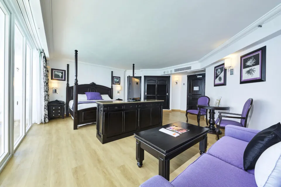 Oceanfront suite seating area and four-poster bed at Hotel Riu Palace Paradise Island.