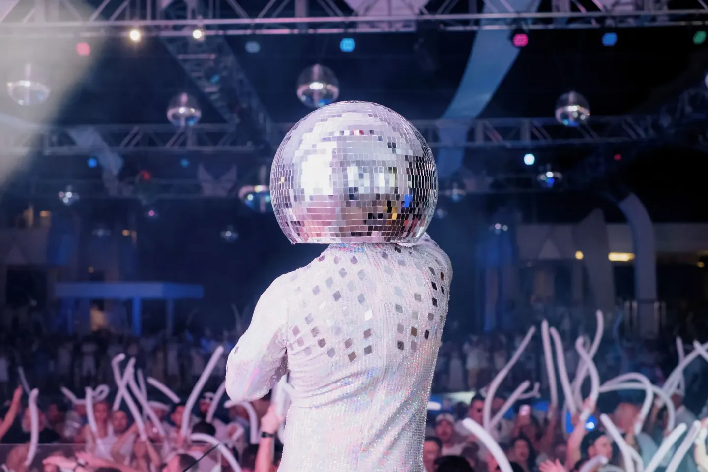 A performer with a mirrored helmet faces a nightclub crowd at Hotel Riu Palace Peninsula.