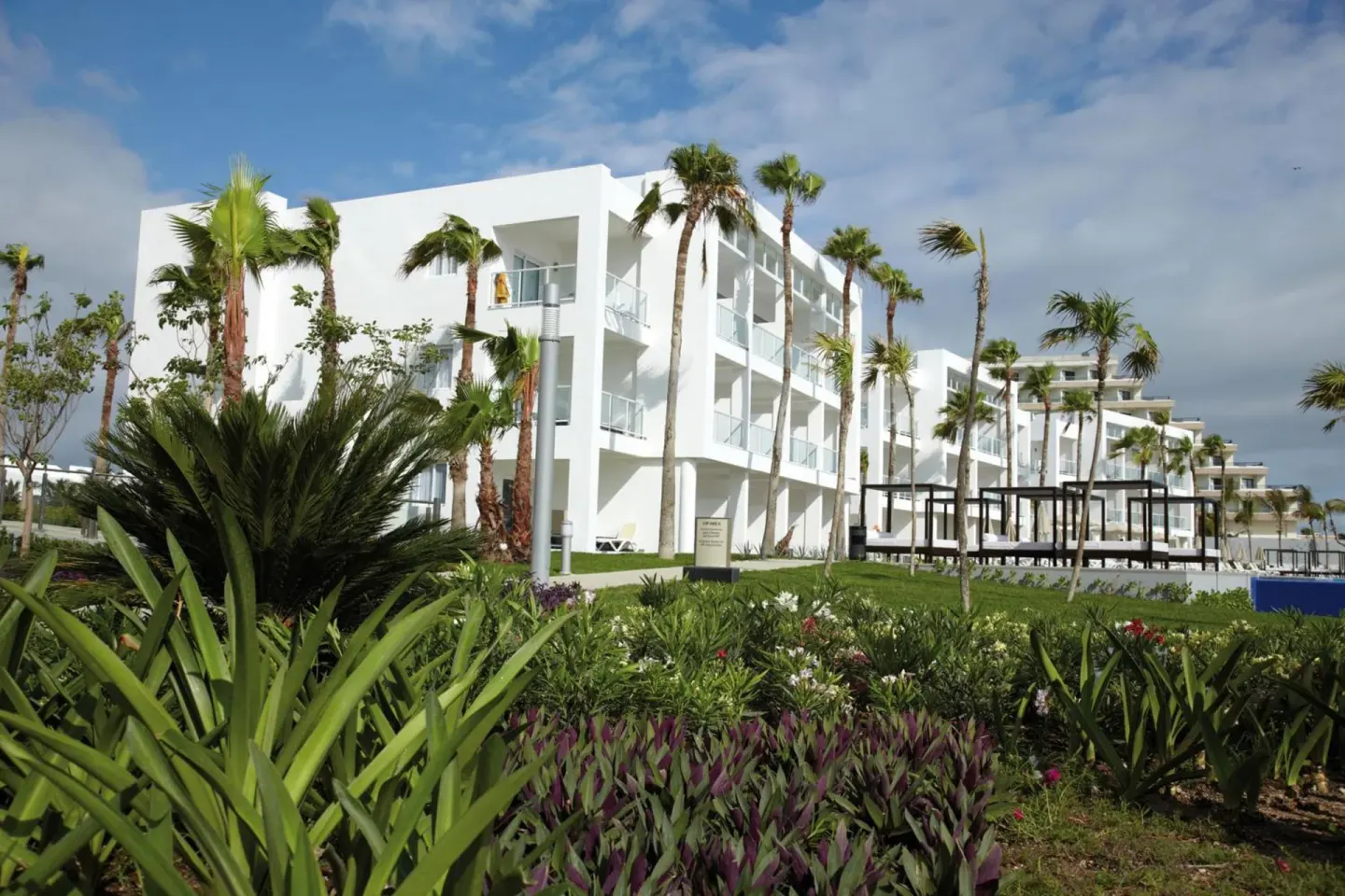 White guest-room building and tropical gardens at Hotel Riu Palace Peninsula.