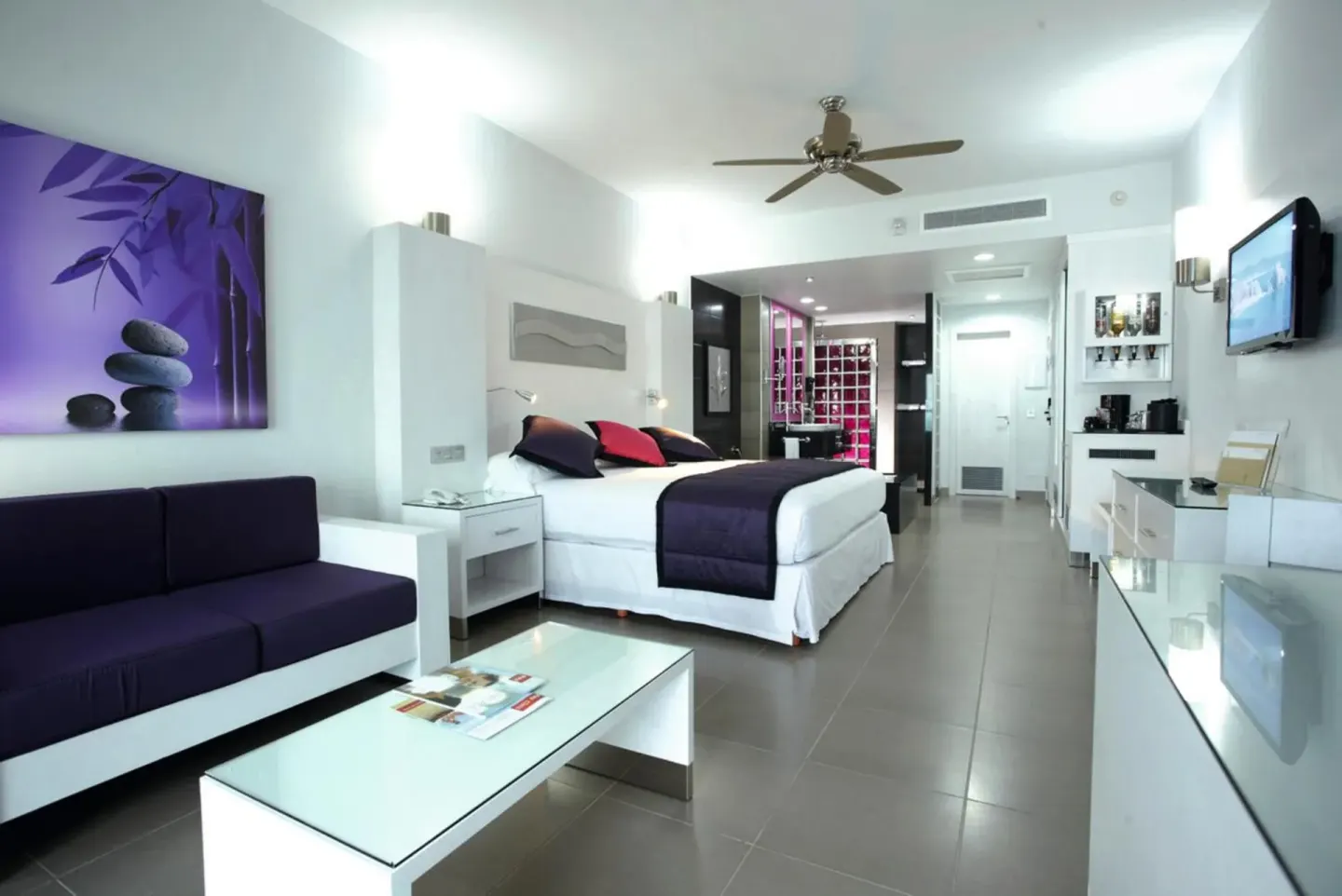 Modern king-bed guest room with purple accents at Hotel Riu Palace Peninsula.