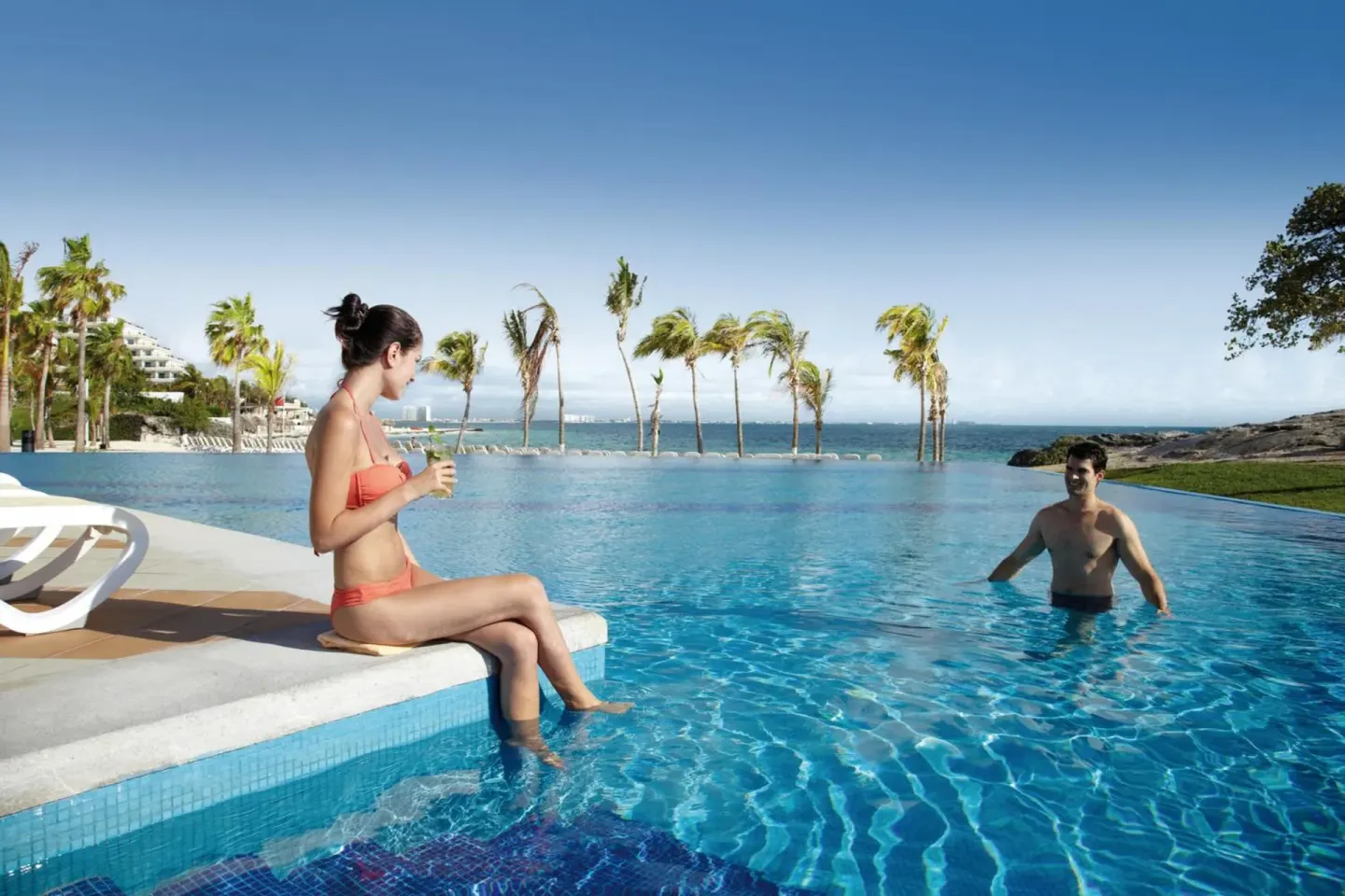 Guests relax by the oceanfront pool at Hotel Riu Palace Peninsula.