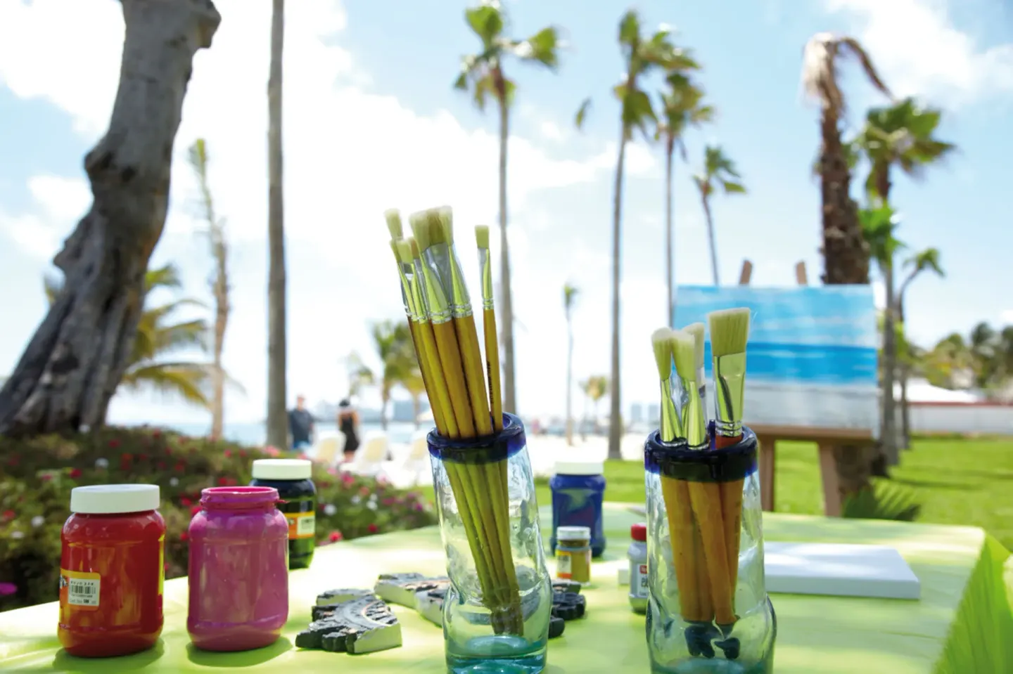 Paint brushes and colorful paints on an outdoor table at Hotel Riu Palace Peninsula.