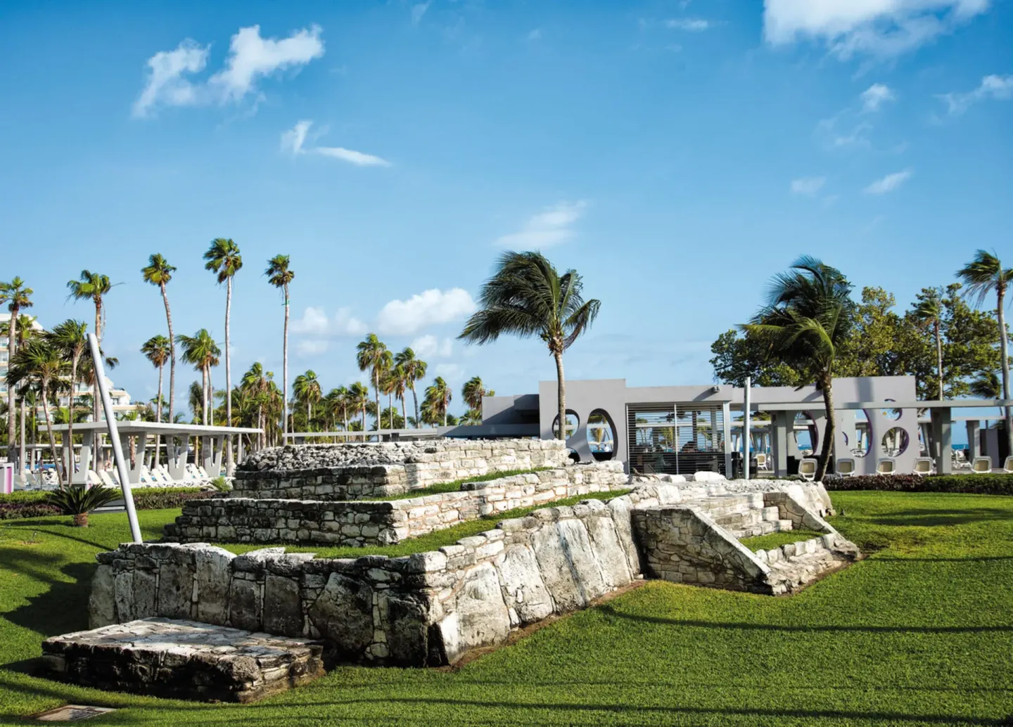 Stone ruins and palm-lined lawn at Hotel Riu Palace Peninsula.