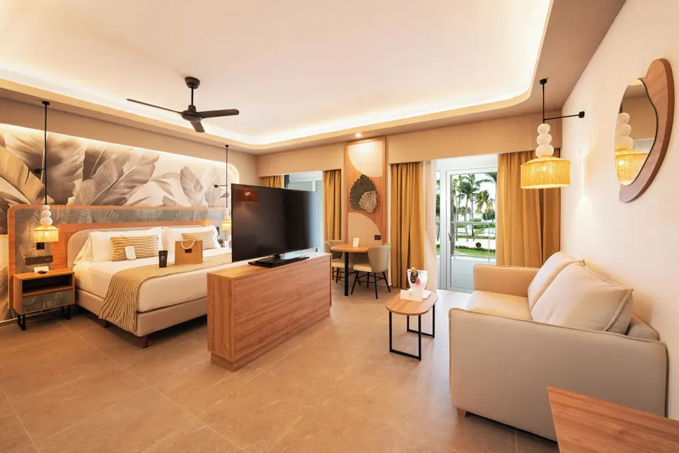 Elite Club Suite with king bed, sofa, TV, and balcony doors at Hotel Riu Palace Peninsula.