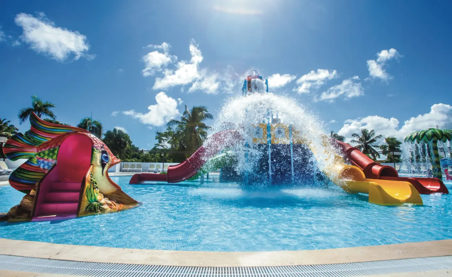 Children's splash area with fish figure, slides, and spraying water at Hotel Riu Palace Punta Cana.