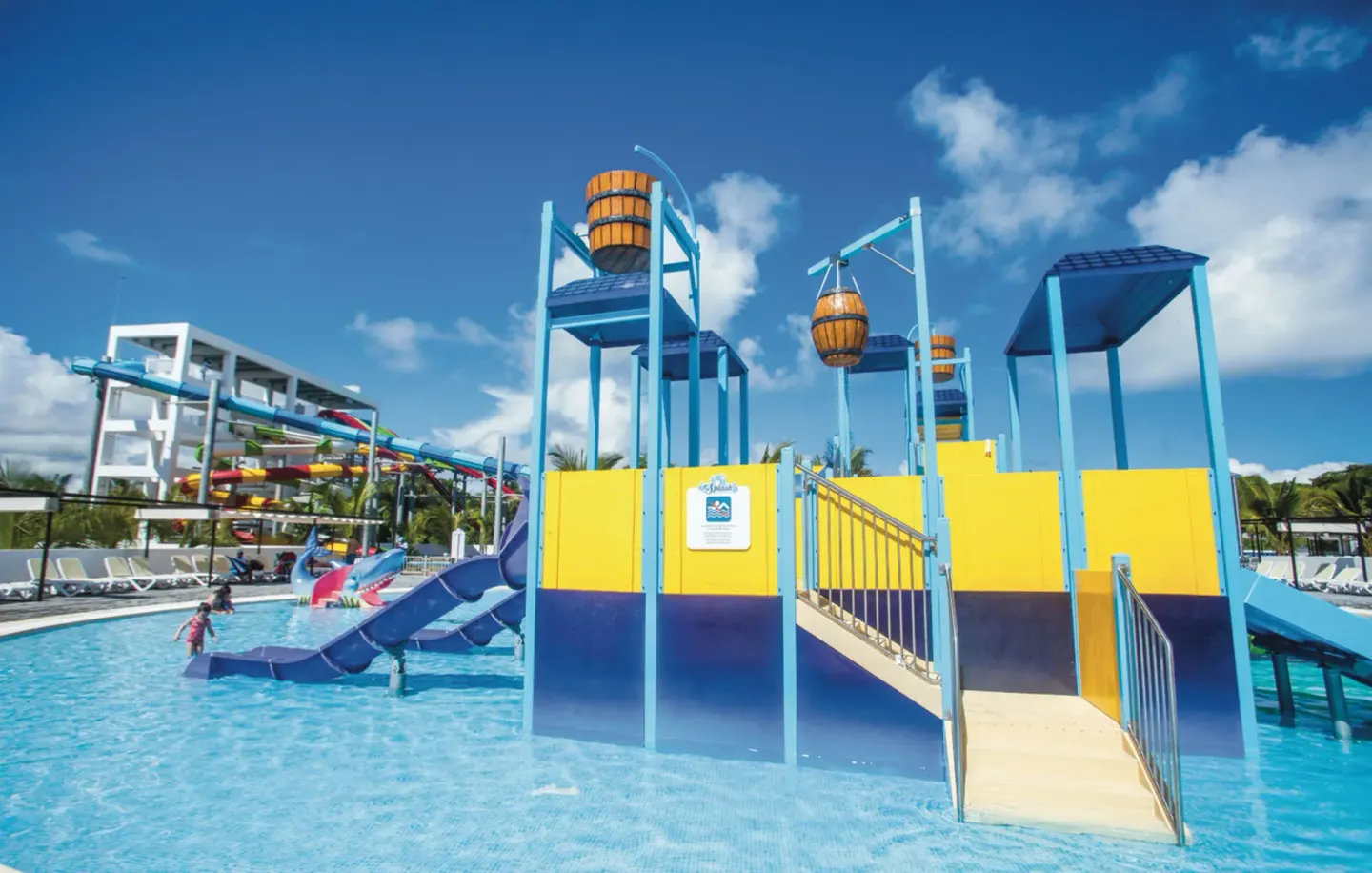 Children's splash structure with slides and tipping buckets at Hotel Riu Palace Punta Cana.