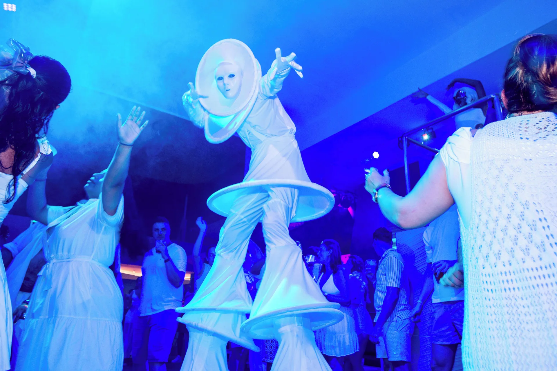 Costumed performer dancing among guests under blue lighting at Hotel Riu Palace Punta Cana.