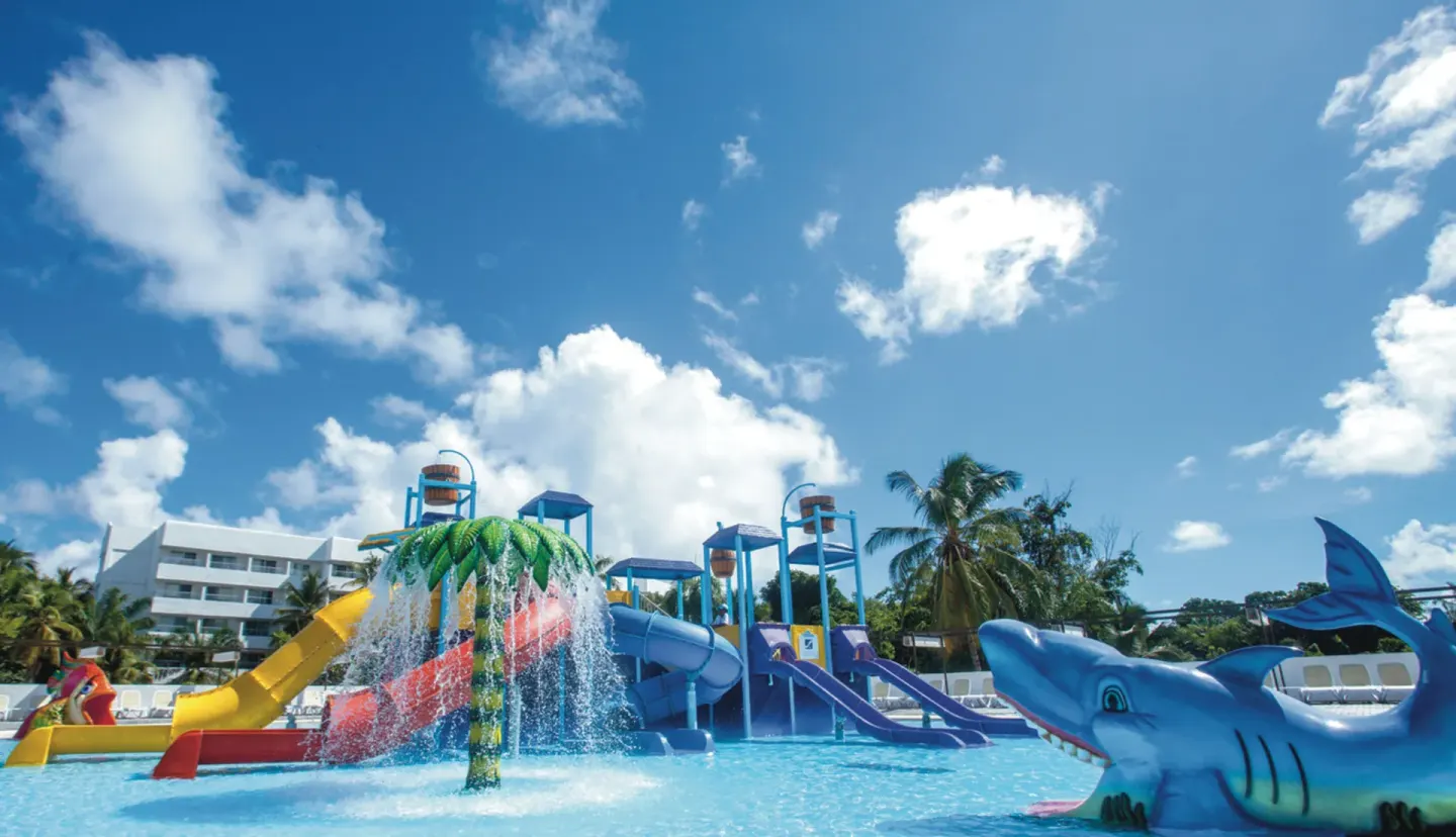 Kids' splash pool with slides and shark figure at Hotel Riu Palace Punta Cana.