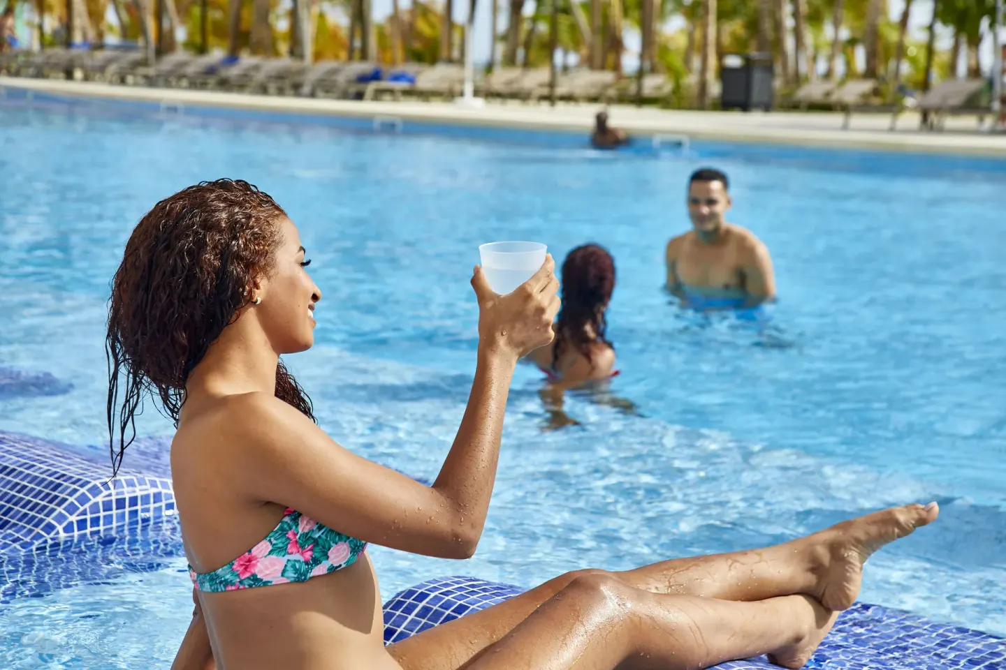 Guest raises a drink while lounging in the pool at Hotel Riu Palace Punta Cana.