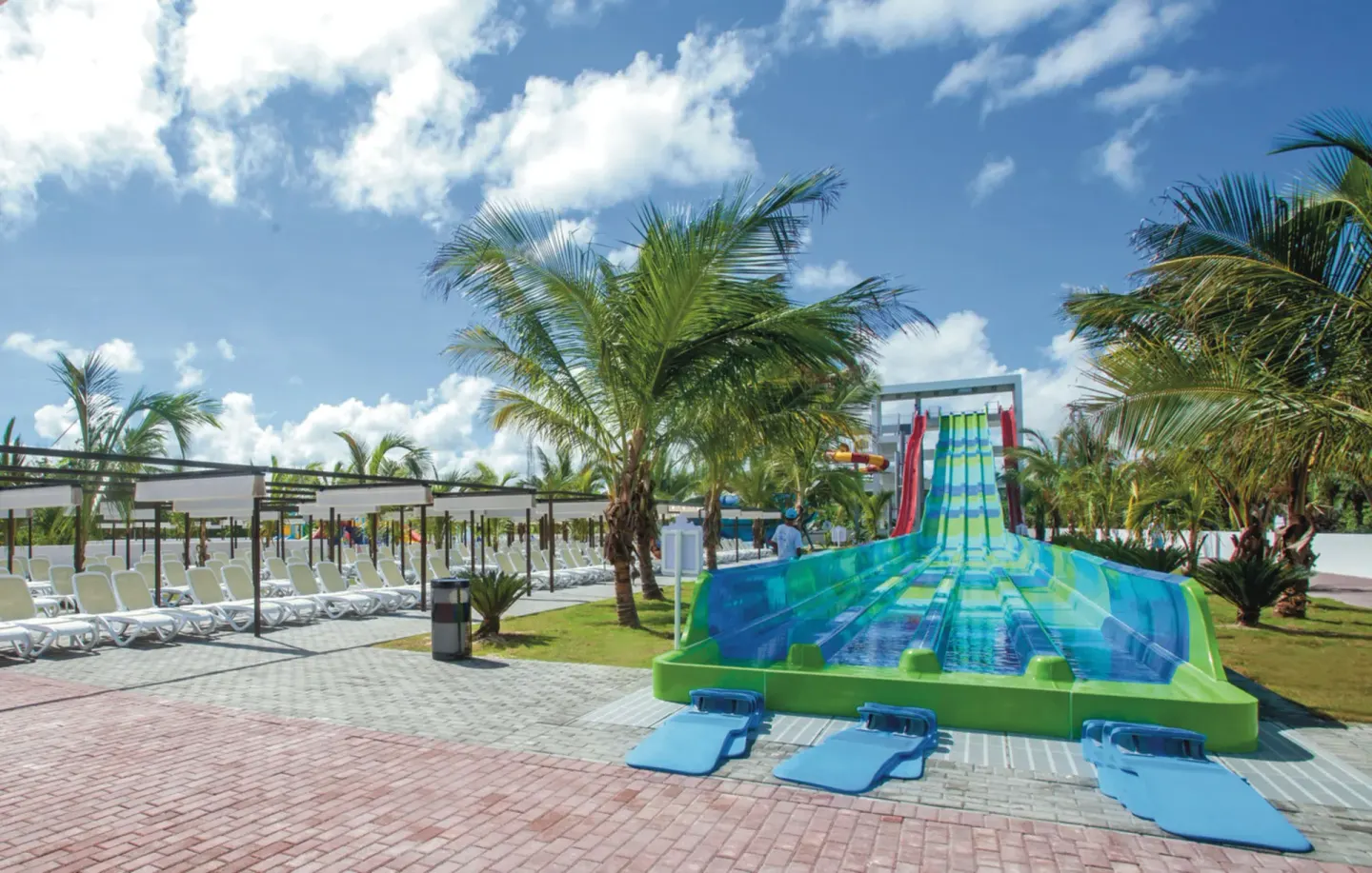 Green and blue water slide beside lounge chairs at Hotel Riu Palace Punta Cana.