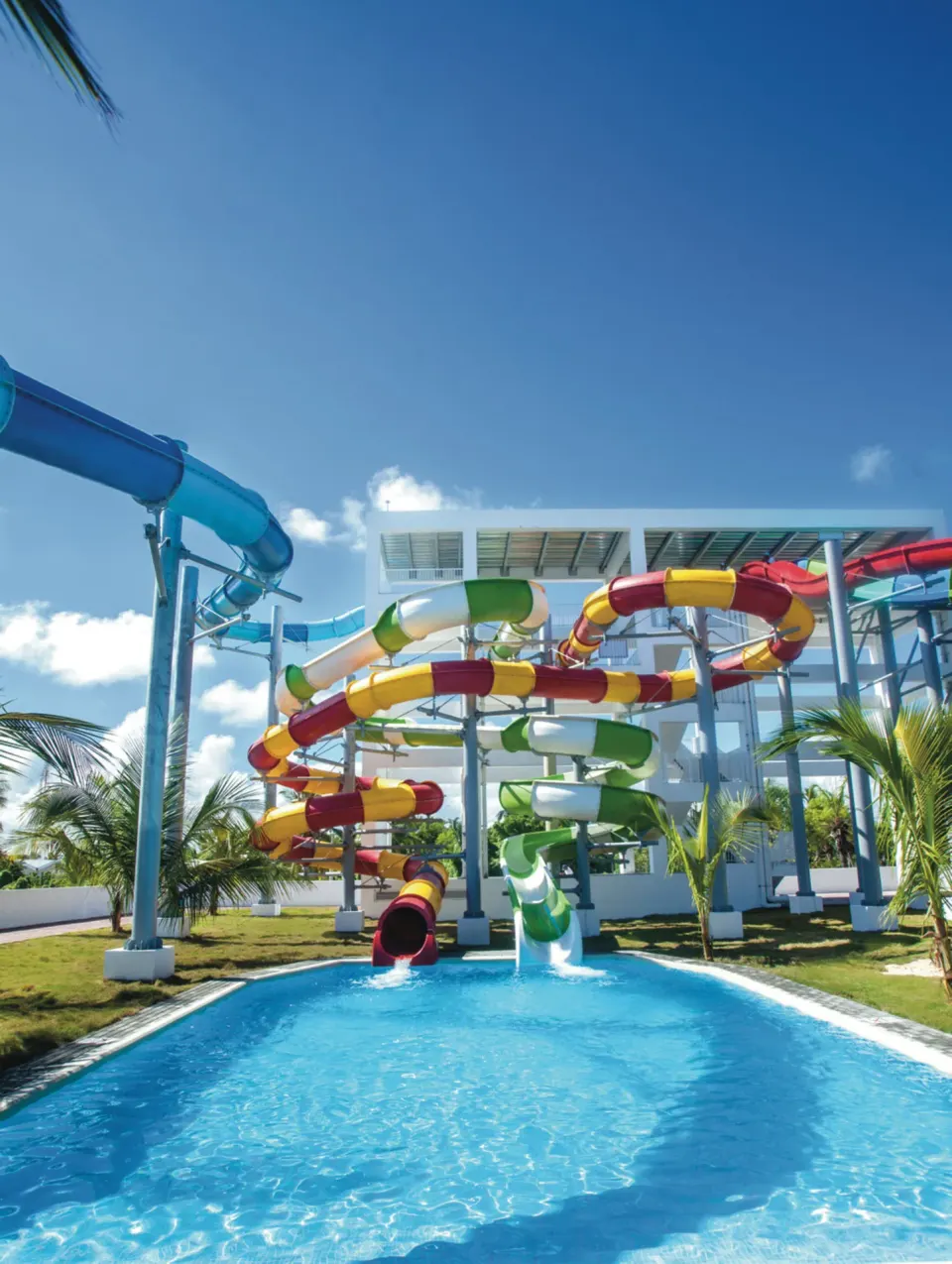 Water slide runouts and elevated tubes under blue sky at Hotel Riu Palace Punta Cana.