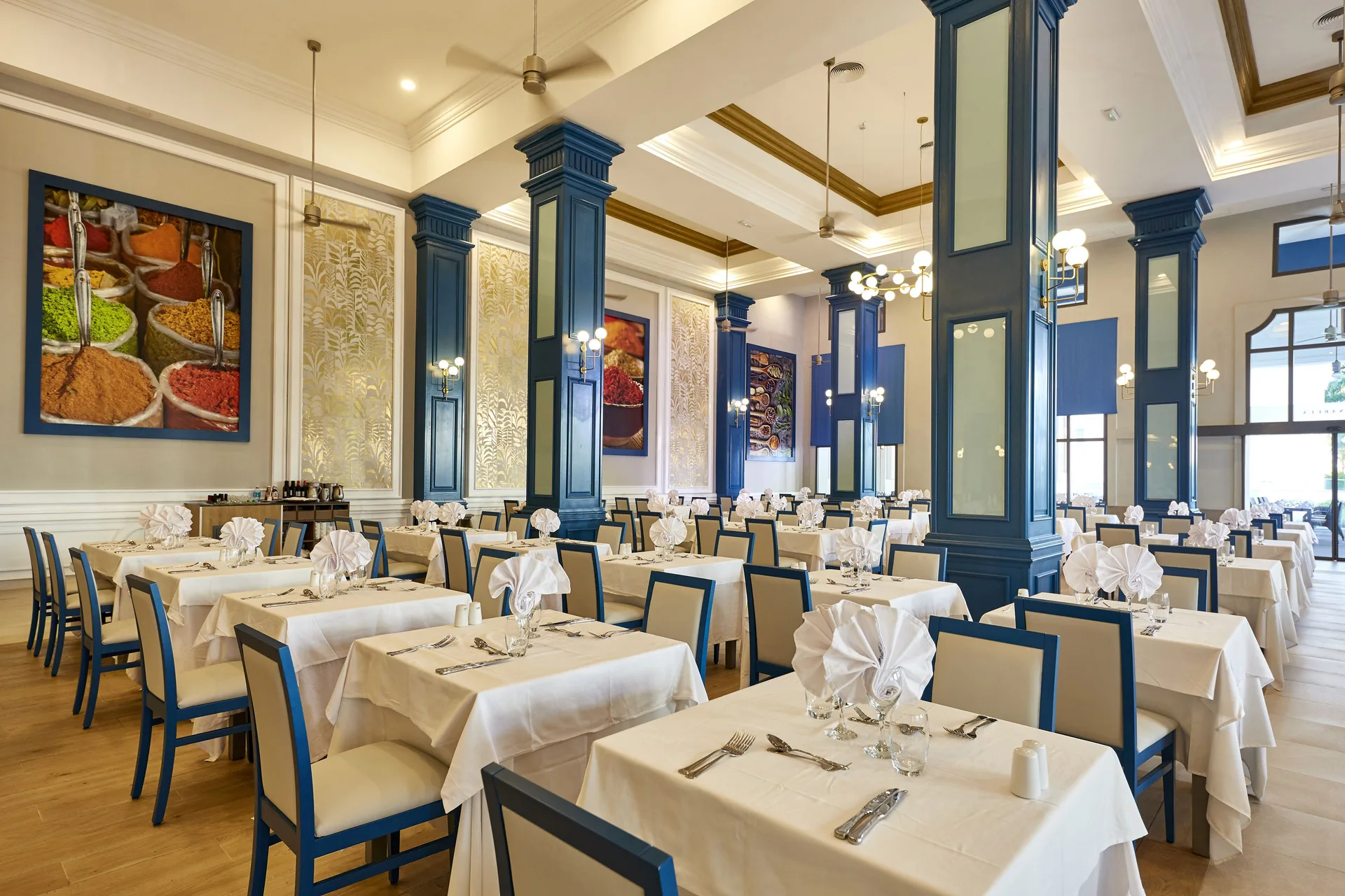 Buffet dining room with blue columns and white tablecloths at Hotel Riu Palace Punta Cana.