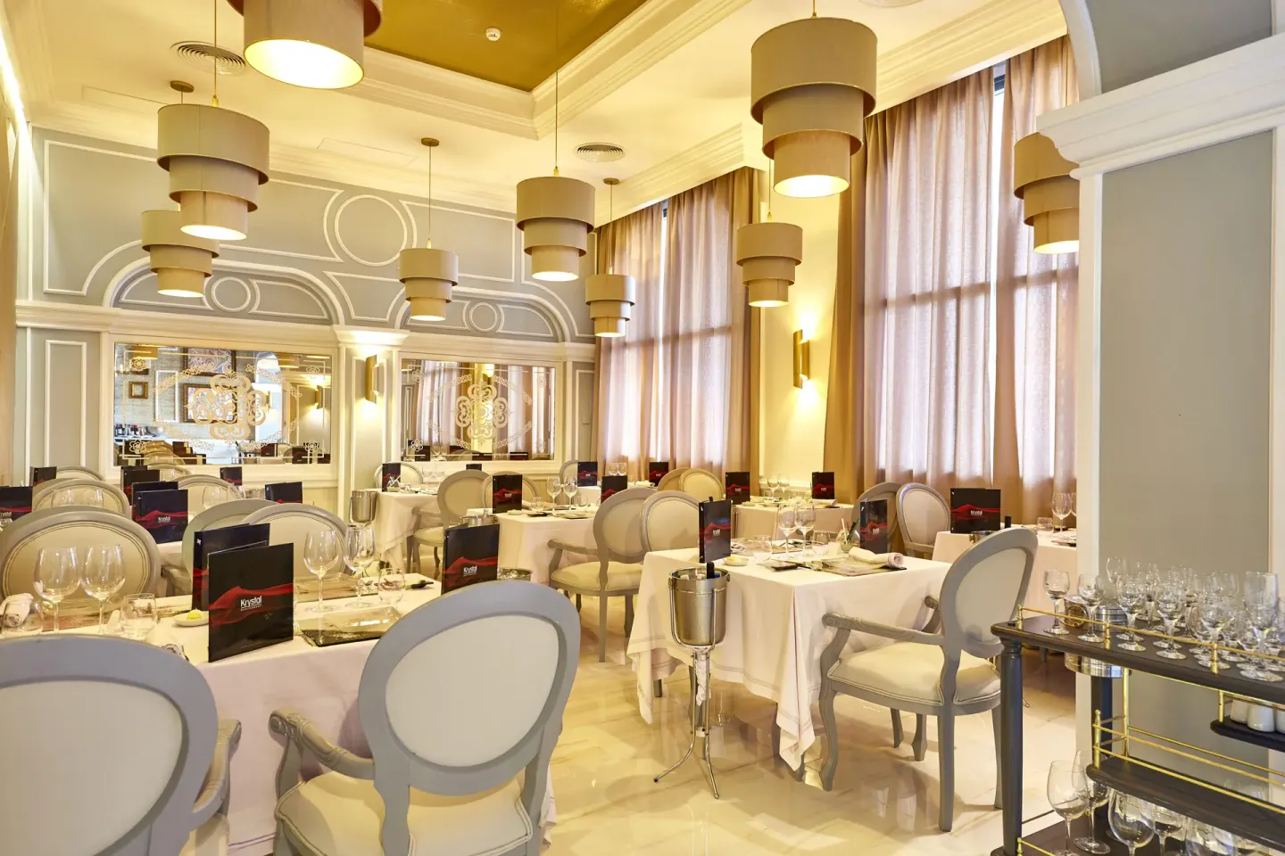 Krystal dining room with set tables and pendant lights at Hotel Riu Palace Punta Cana.