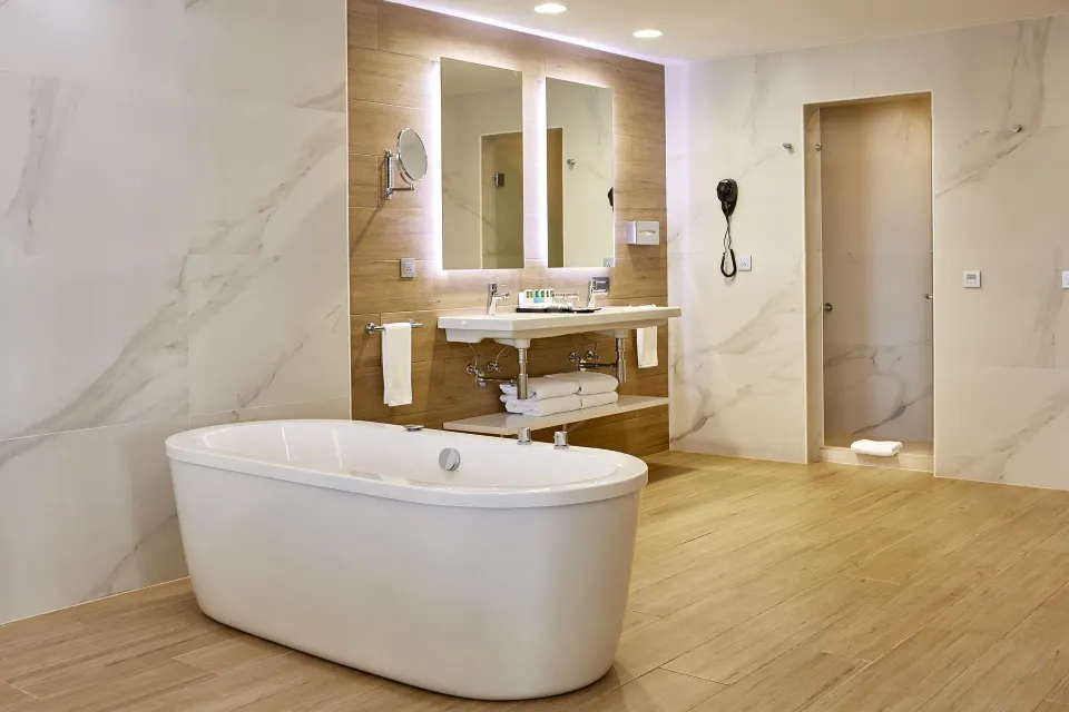 Suite bathroom with freestanding tub, double mirrors, vanity, and shower at Hotel Riu Palace Punta Cana.
