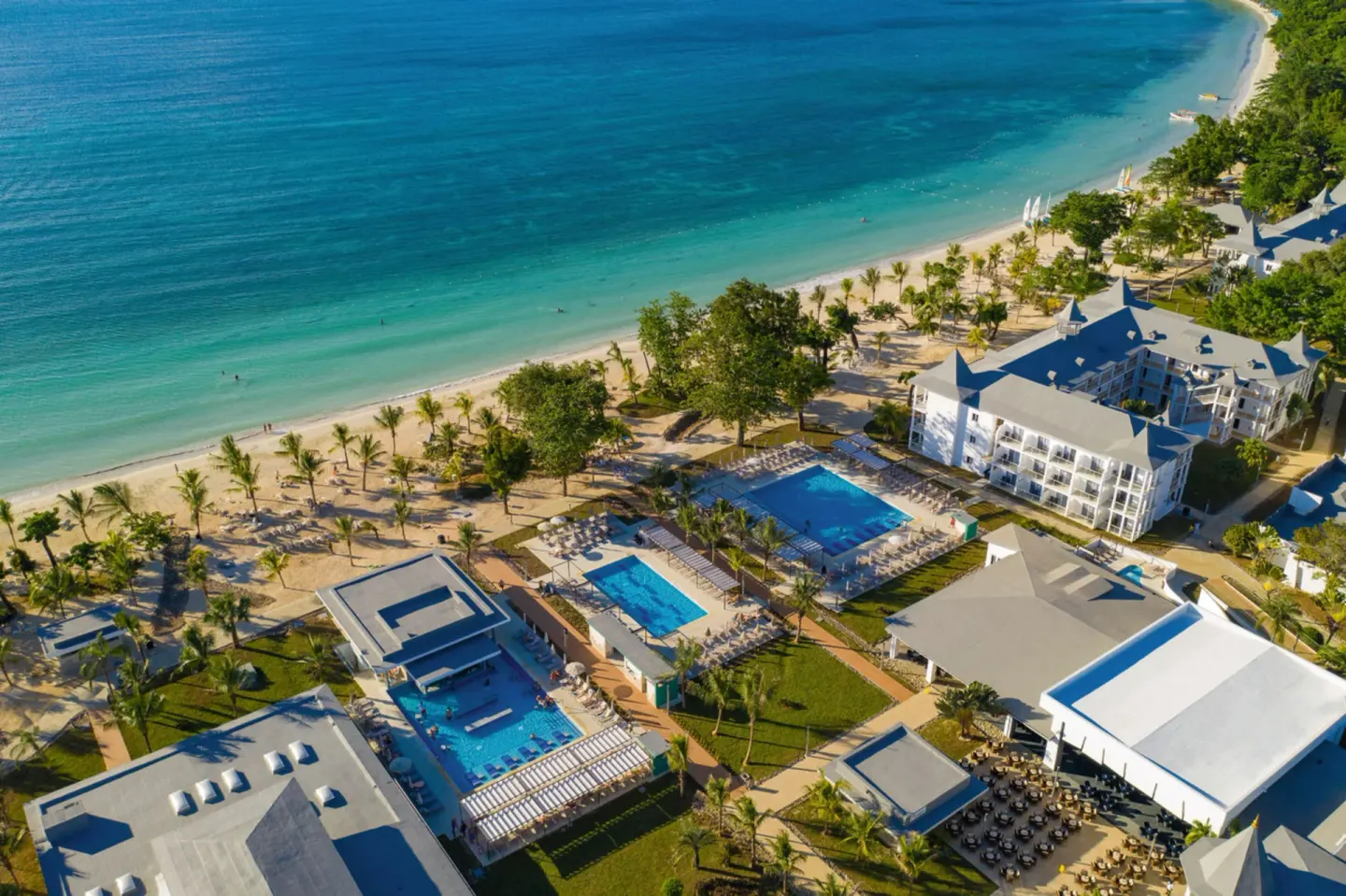 Aerial view of pools, buildings, and beach at Hotel Riu Palace Tropical Bay.