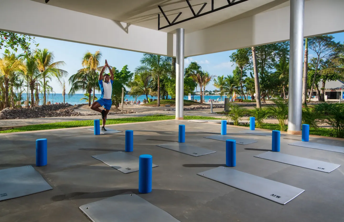 Outdoor yoga mats set under a pavilion by the beach at Hotel Riu Palace Tropical Bay.