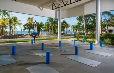 Outdoor yoga mats set under a pavilion by the beach at Hotel Riu Palace Tropical Bay.