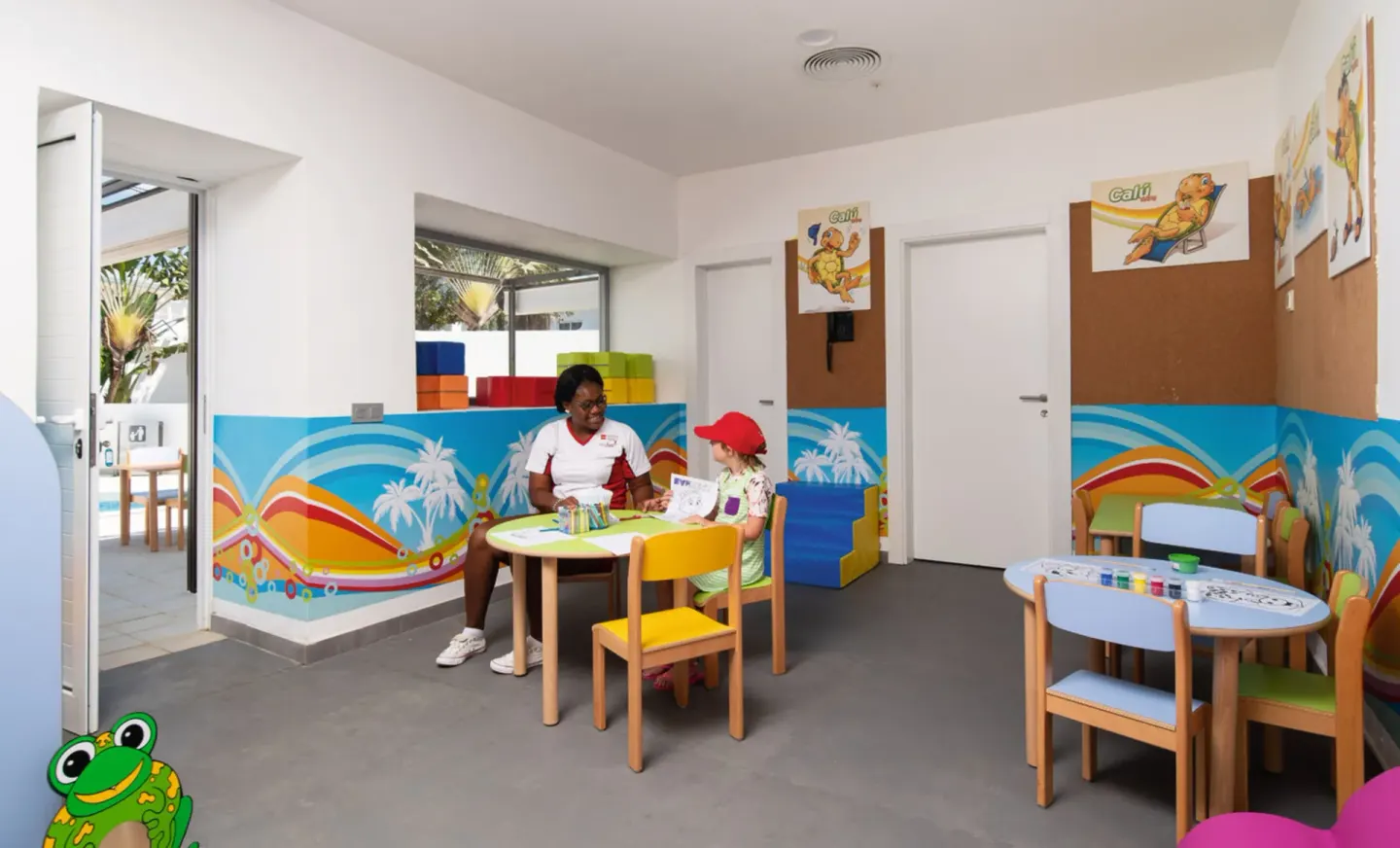 Children’s activity room with small tables and colorful wall art at Hotel Riu Palace Tropical Bay.