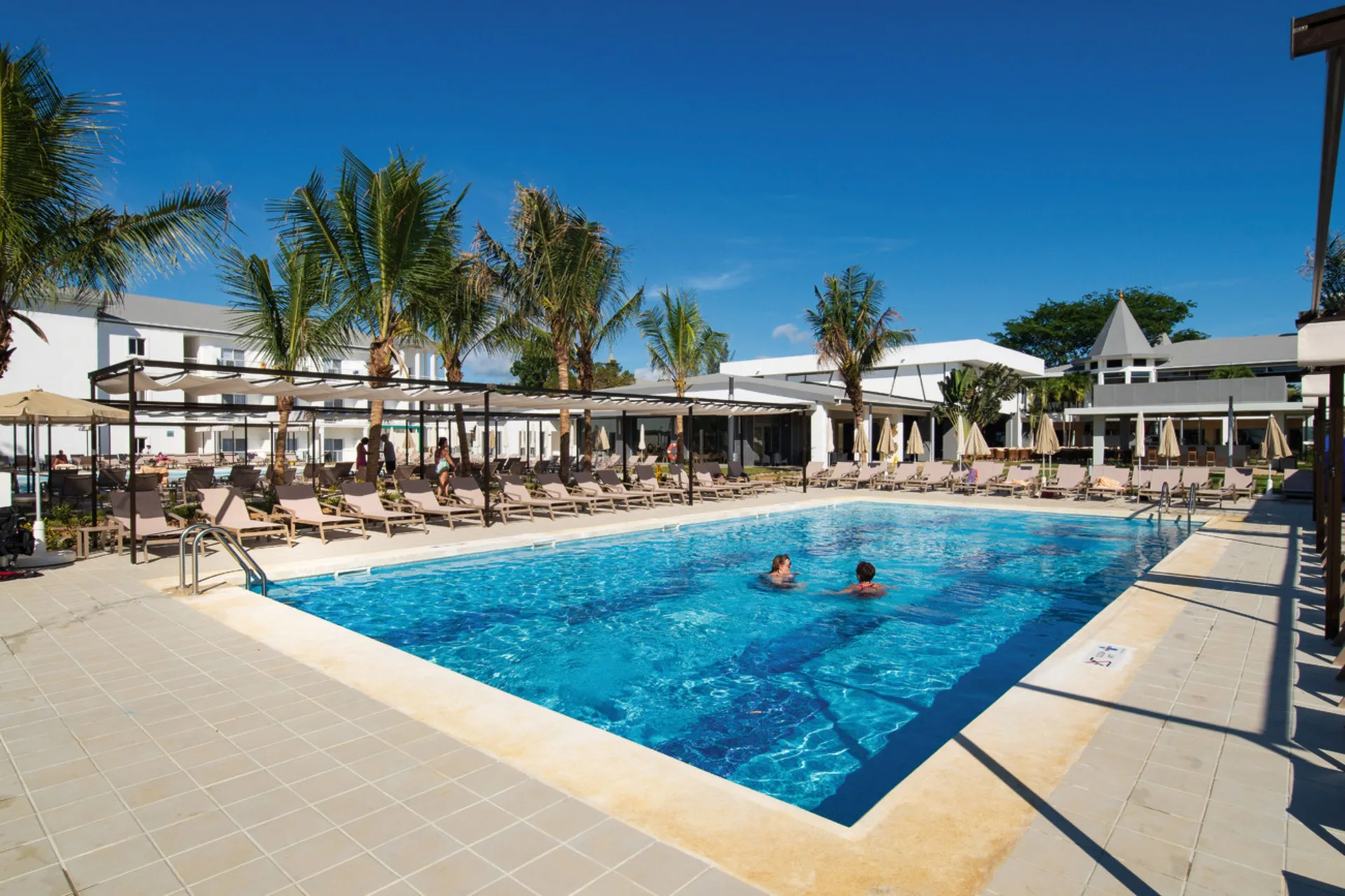 Main pool with loungers and palms at Hotel Riu Palace Tropical Bay.