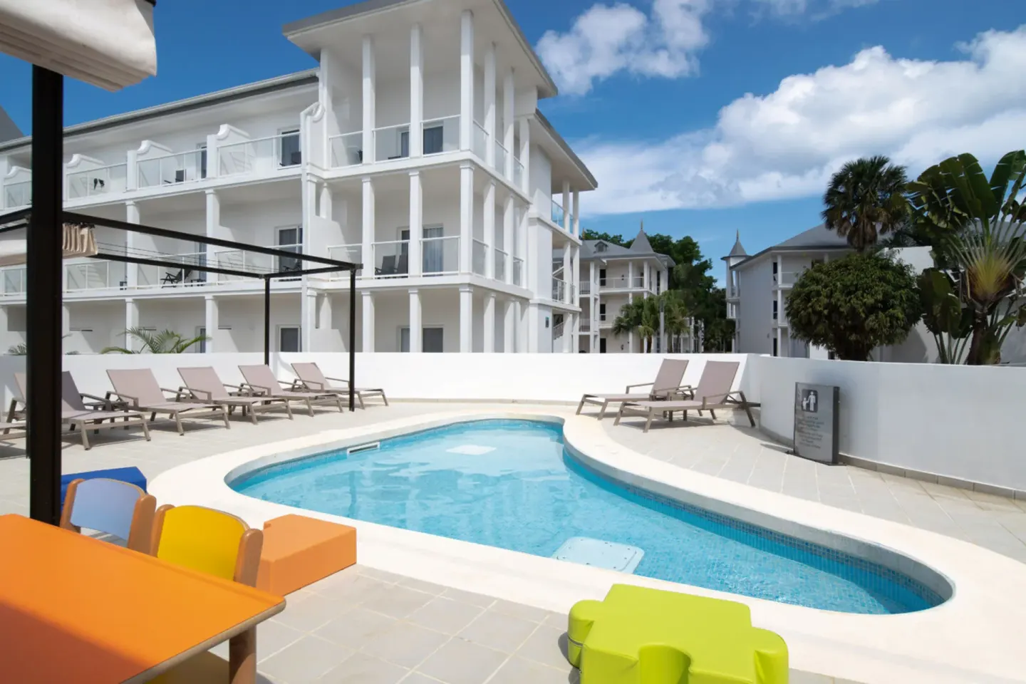 Small outdoor pool with loungers beside white resort buildings at Hotel Riu Palace Tropical Bay.