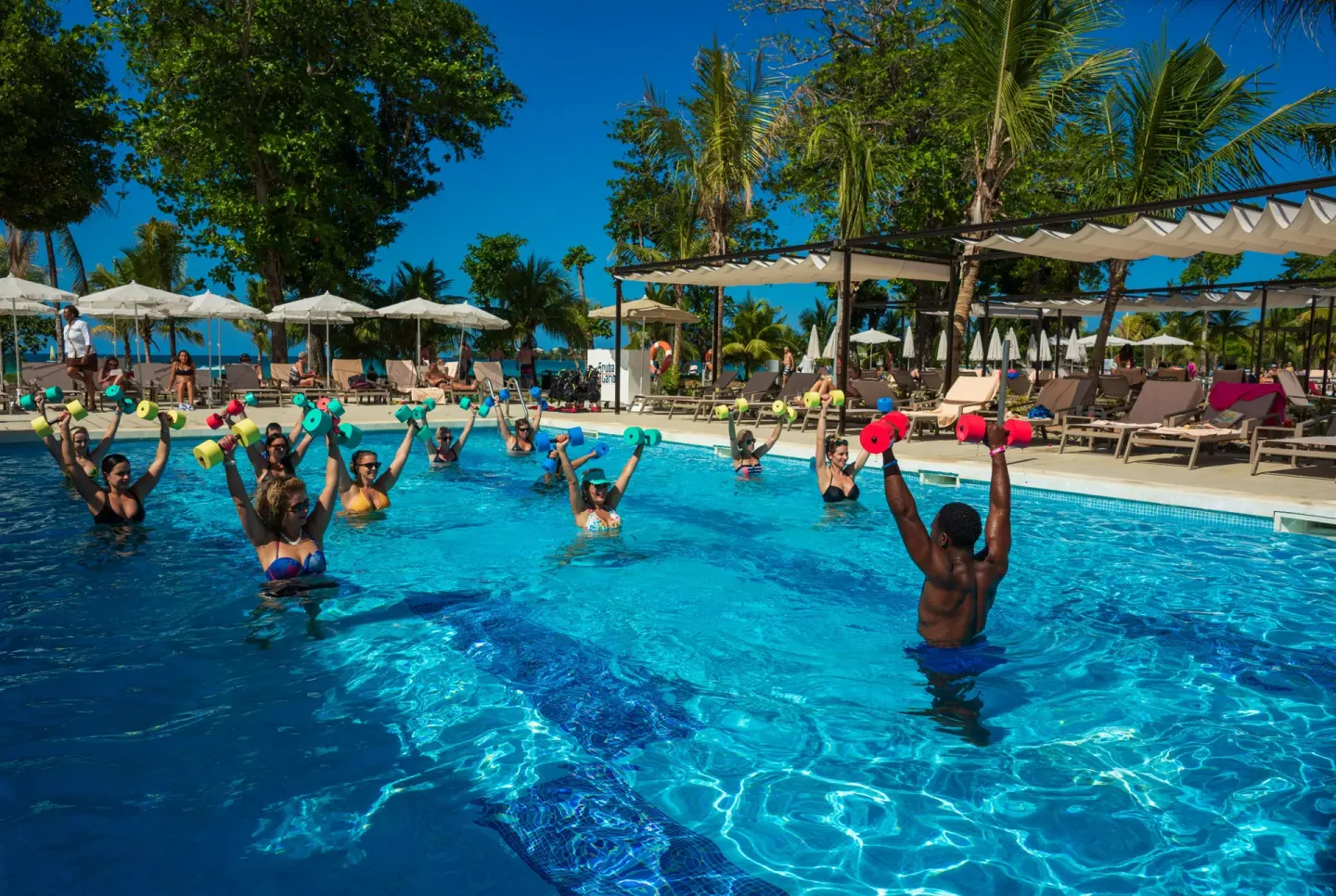 Guests raise foam weights during pool aerobics at Hotel Riu Palace Tropical Bay.