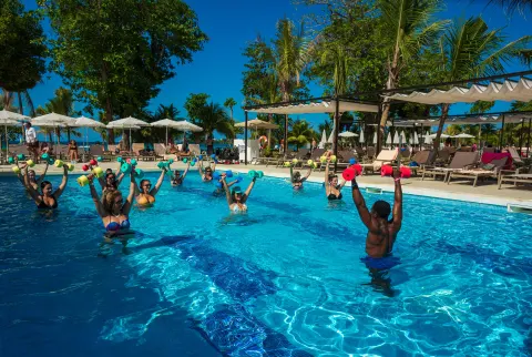 Guests raise foam weights during pool aerobics at Hotel Riu Palace Tropical Bay.