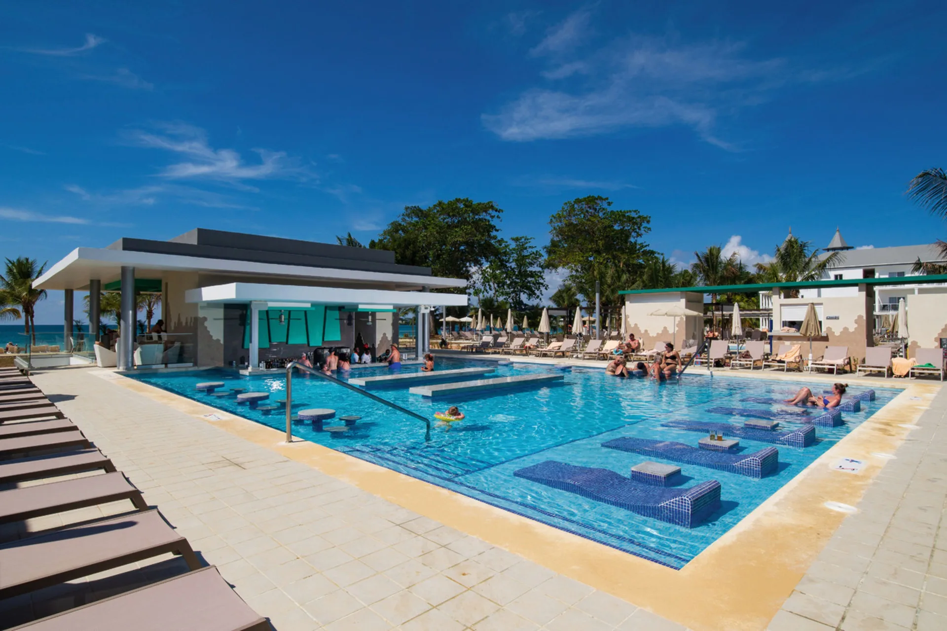 Pool with swim-up bar and submerged loungers at Hotel Riu Palace Tropical Bay.