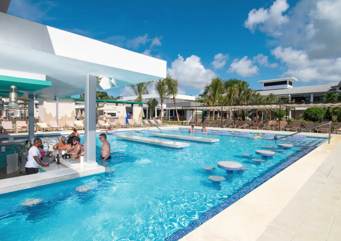Pool with swim-up bar and in-water stools at Hotel Riu Palace Tropical Bay.