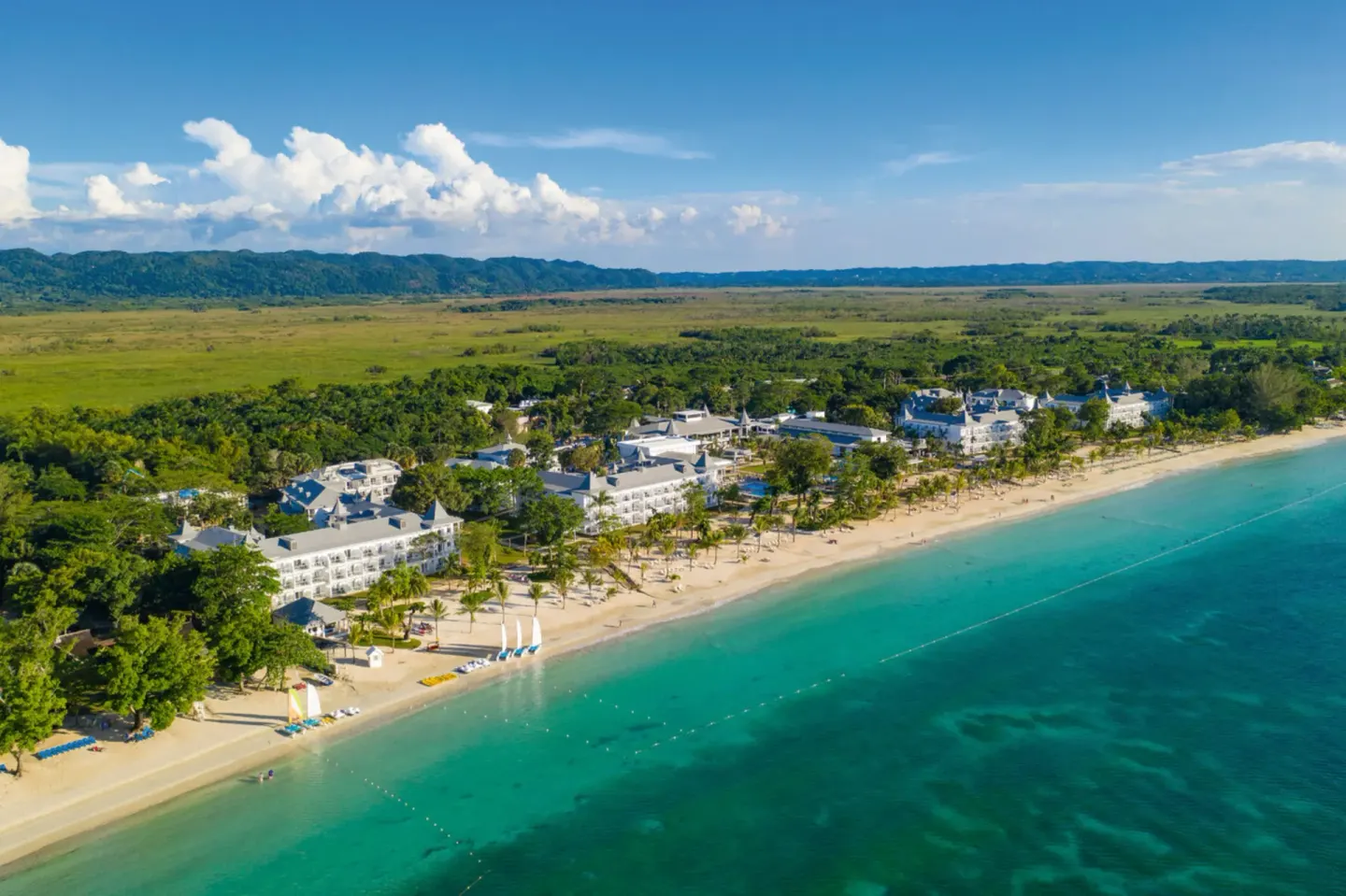 Wide aerial view of Hotel Riu Palace Tropical Bay beside the beach and lagoon-blue sea.