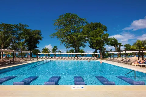 Wide pool view with in-water loungers and ocean backdrop at Hotel Riu Palace Tropical Bay.